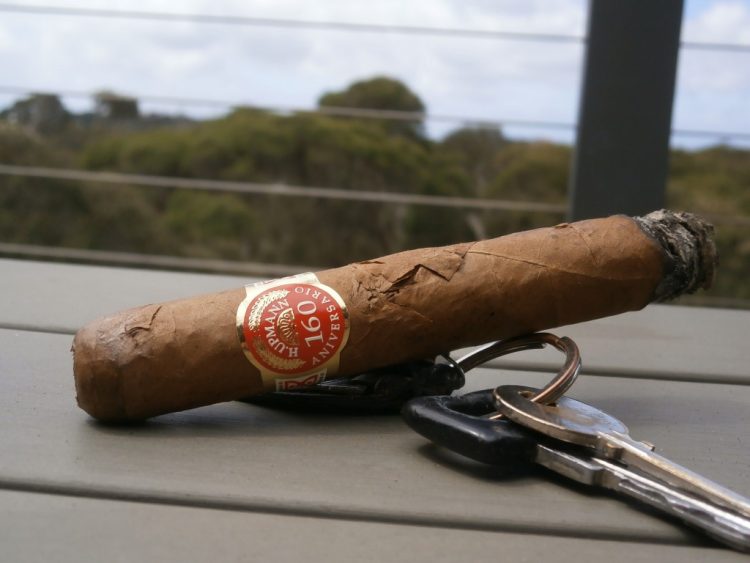H. Upmann Prominentes 160th Aniversario Humidor, a quarter burnt, with some car keys